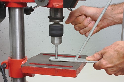 Pillar drill being used to drill steel