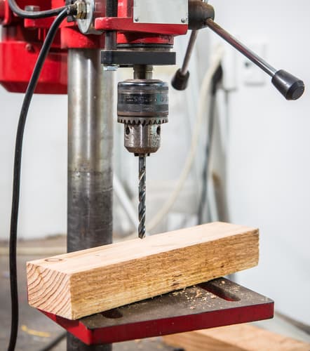 Pillar drill being used to drill thick wood