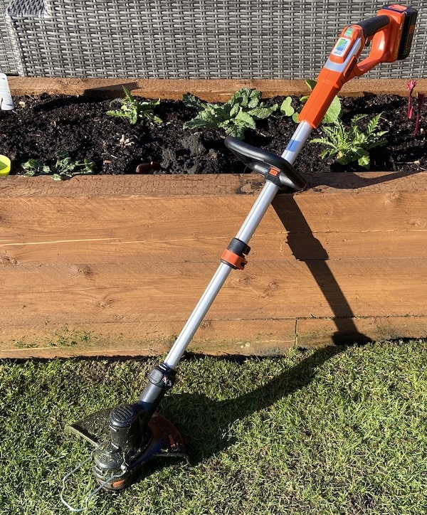Black + Decker 36v strimmer after using on lawn against raised bed