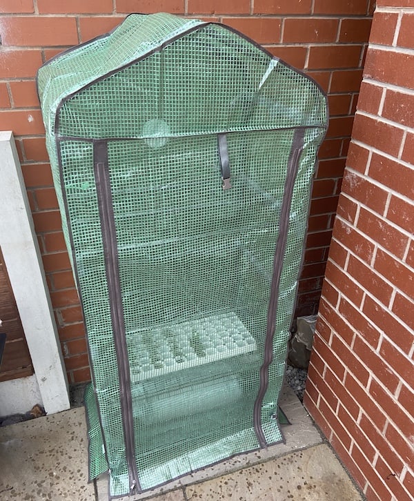 Mini grow house with door closed protecting plants from cold
