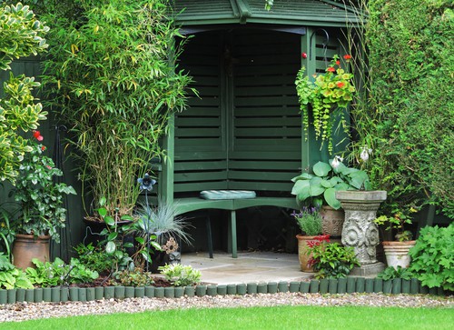 Arbour seat in corner of garden and treated with green paint