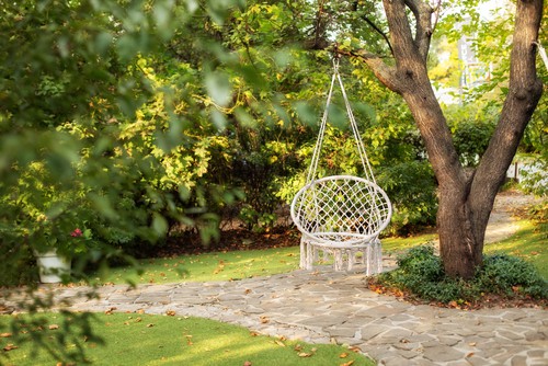 Outdoor hanging hammock chair hanging from tree in garden