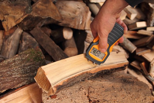 Two pin moisture meter testing firewood for moisture content level