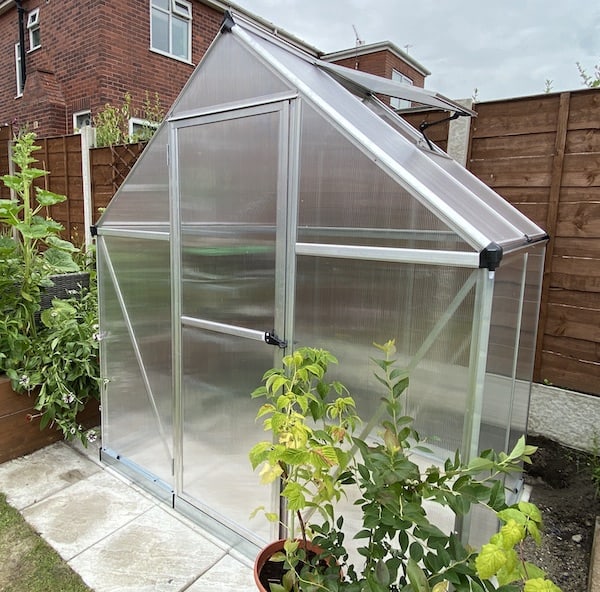 Positioning greenhouse on patio area ready for securing to ground