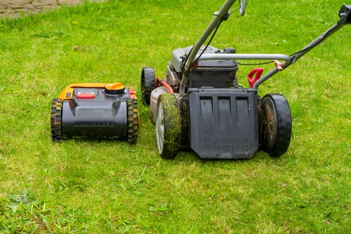 Robot lawn mower for large gardens next to petrol lawn mower.