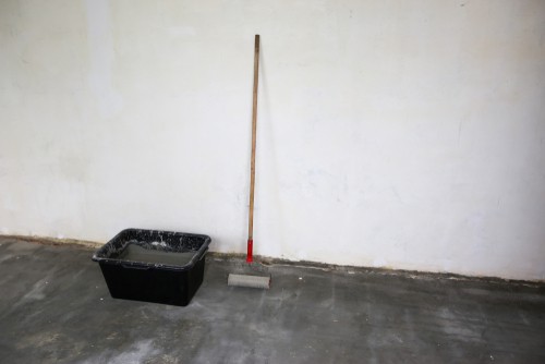 Large paint bucket and roller ready for painting garage floor