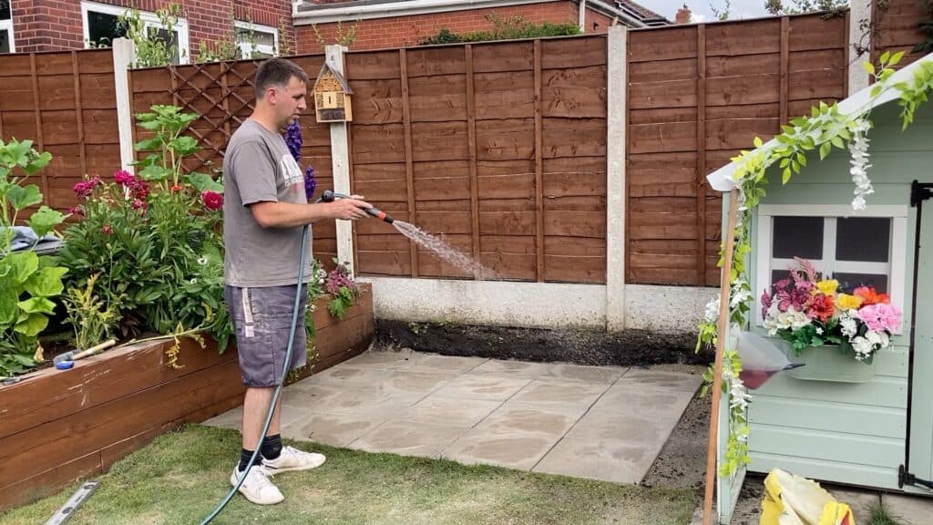 Washing down flags to clean them off and help the dry mix set as the water runs through the cracks