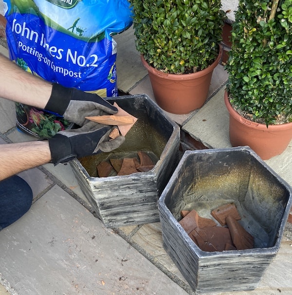 Covering holes with broken pot to stop the holes getting clogged up