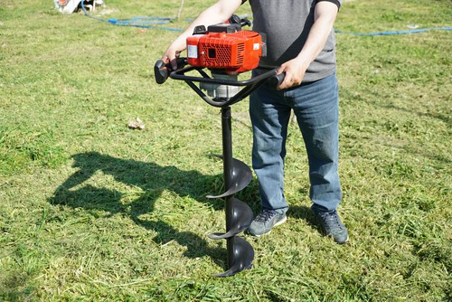 Petrol earth auger being used to dog fence post holes for new paddock