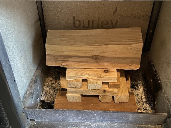 Adding third large log on top of kindling, this step is optional