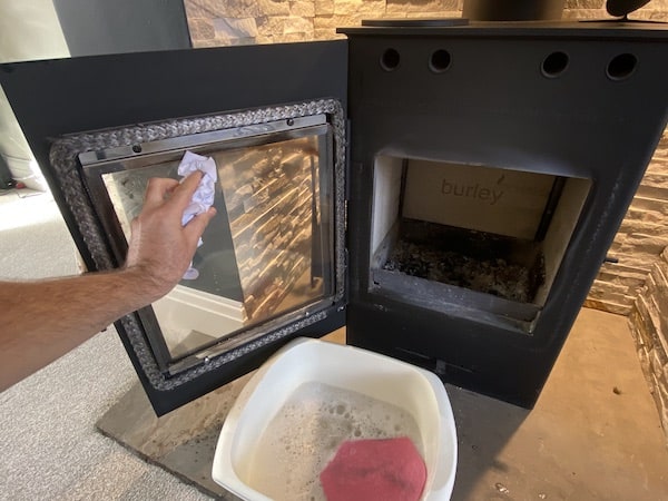 Using screwed up piece of paper dipped in water and wash to clean stove glass