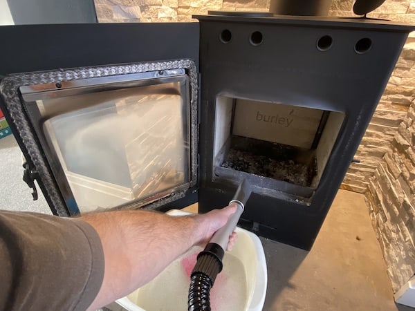 Vacuuming wood burning stove before cleaning glass