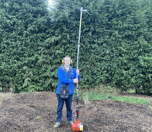 Long reach hedge trimmer with the trimmer head rotated 90 degrees for trimming the top of hedges