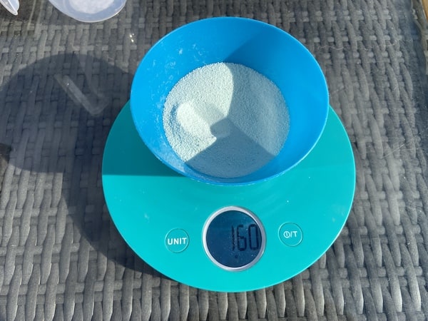 Measuring out 160g of iron sulphate to mix with 16 litres of water and treat an area of 16 square meters