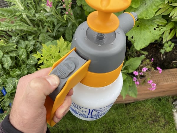 pushing trigger to lock the pressure in the on position for consistent spraying