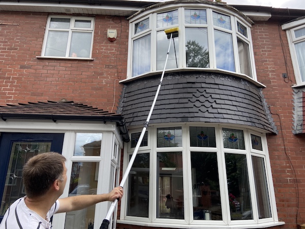 Using the squeegee on the window cleaning pole to clean 1sr floor windows and leave then streak free